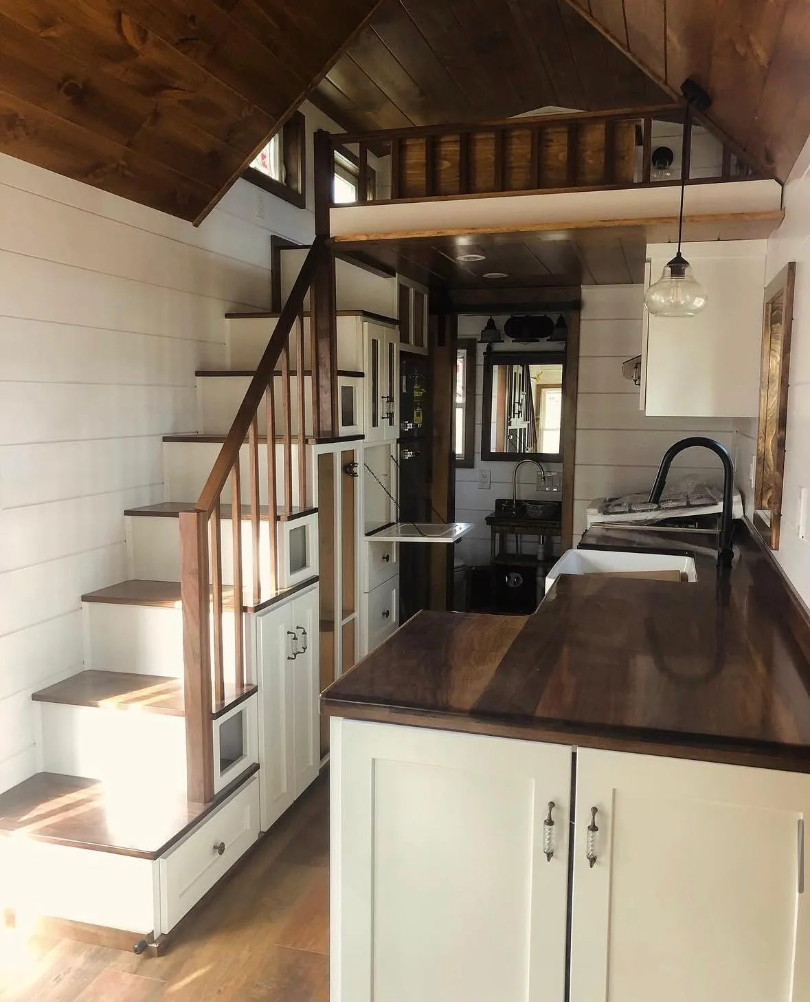 Interior with a staircase rising to the sleeping loft beside a galley kitchen with a walnut counter